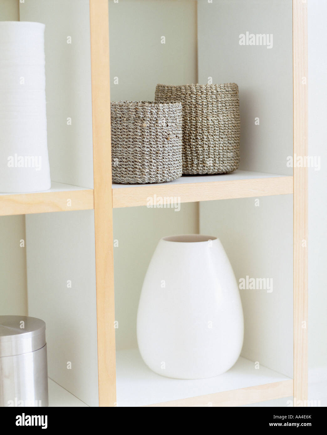 Close-up de sisal beige cylindriques paniers de stockage et vase en céramique blanche sur étagères modernes Banque D'Images