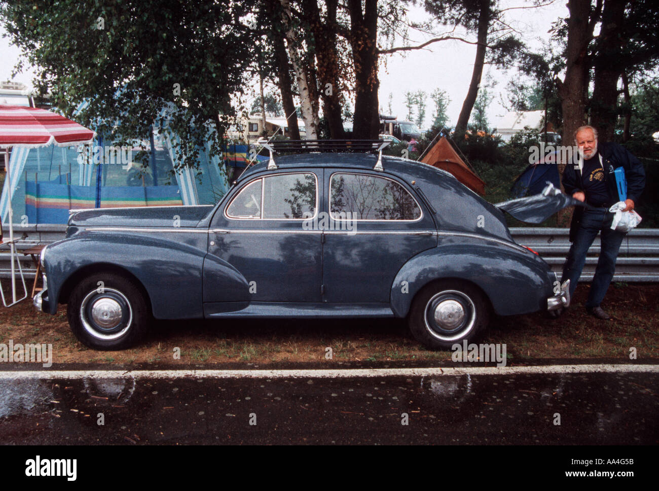 Classic 1950 Peugeot 203 voiture sur un camp français site avec un homme barbu chargement du boot trunk Banque D'Images