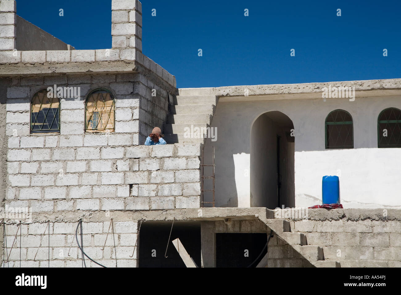 Girl peering over le mur d'une maison neuve, Quilotoa Equateur Banque D'Images