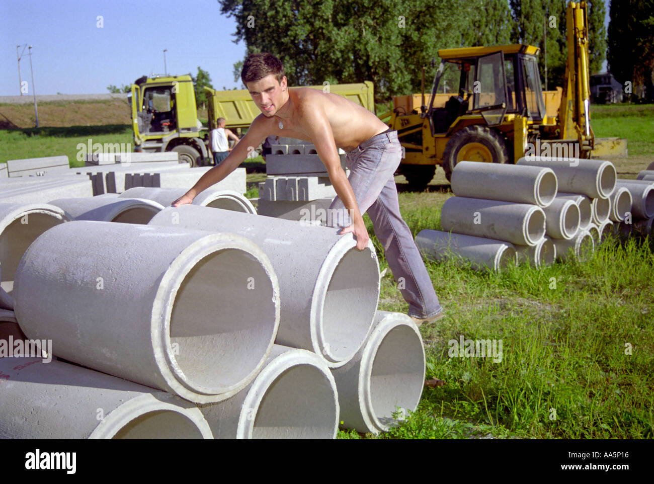 Les jeunes hommes est porteur du travail travailleur tuyau gris ciel bleu le gravier Sisak Croatie fun blue-jeans Banque D'Images