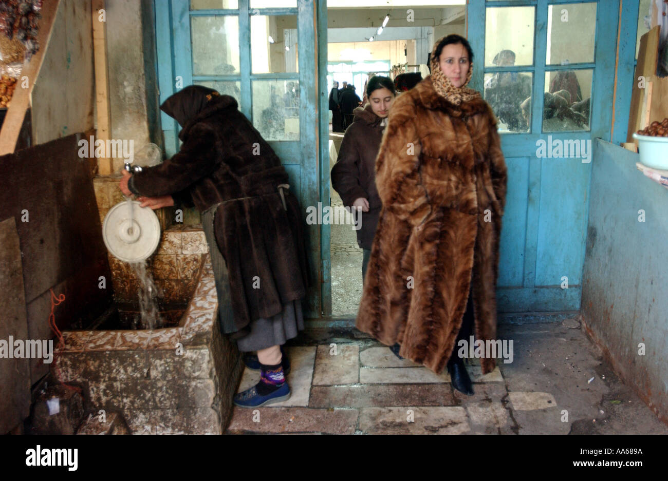 Bakou Azerbaïdjan 11 janvier 2003 Azeribajiani femmes portant des manteaux de fourrure, sortir d'un marché où l'Vvndors vendent leurs fruits Banque D'Images