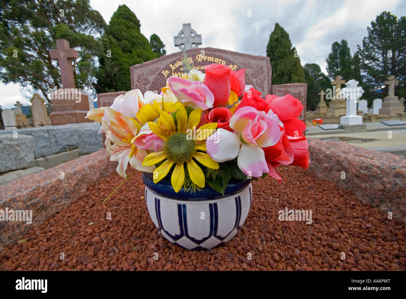 Fleurs en plastique lumineux ornant une tombe dans un cimetière Banque D'Images