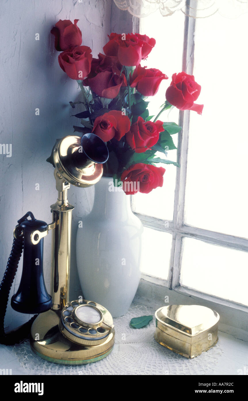 Téléphone chandelier en fenêtre avec vase de roses rouges Banque D'Images