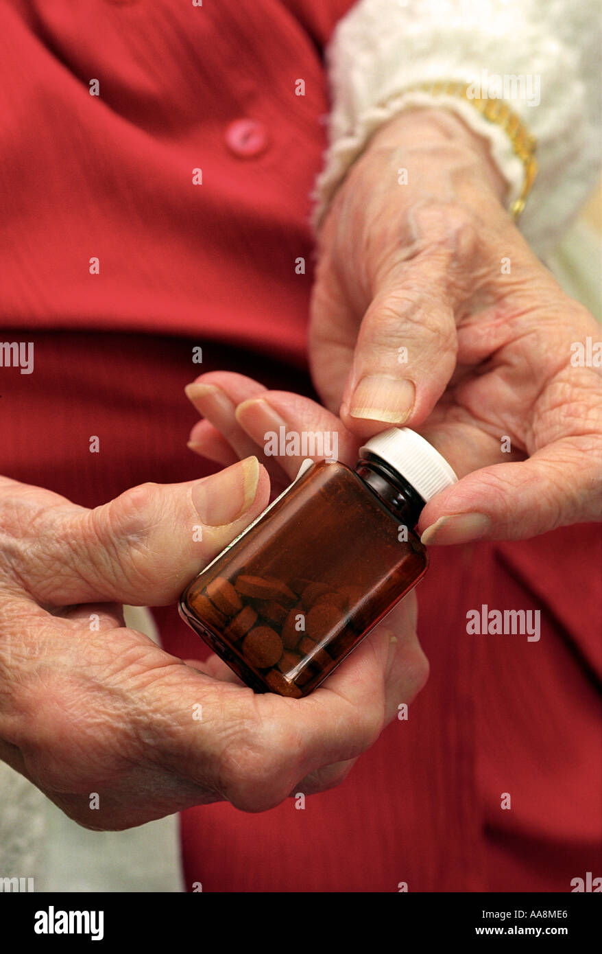 Une vieille dame avec une forme grave d'arthrite d'essayer d'ouvrir une bouteille de pilules Banque D'Images