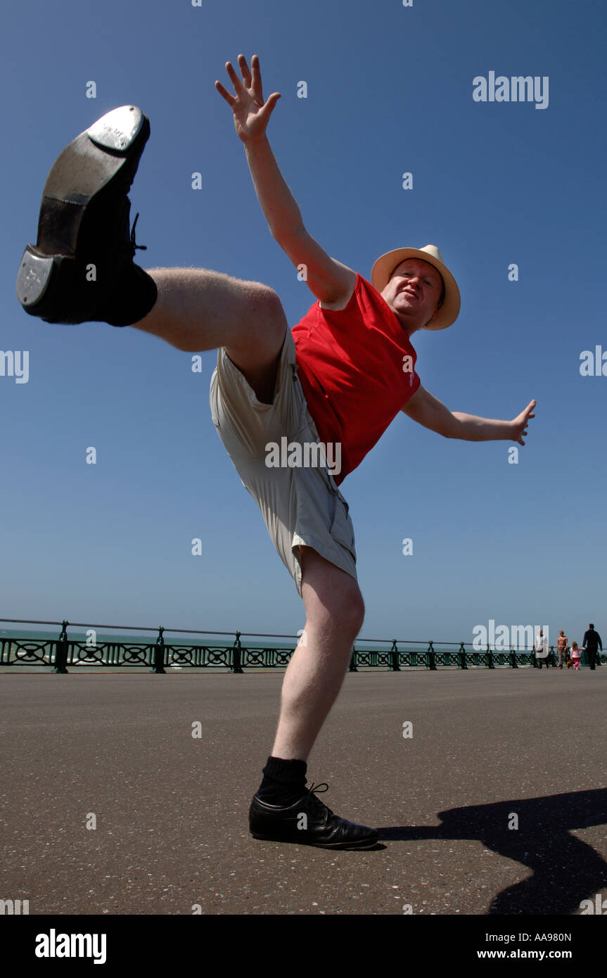 Un excès de middle-aged man doing maladroit kicking élevé danse de routine sur le front de mer de Brighton Banque D'Images