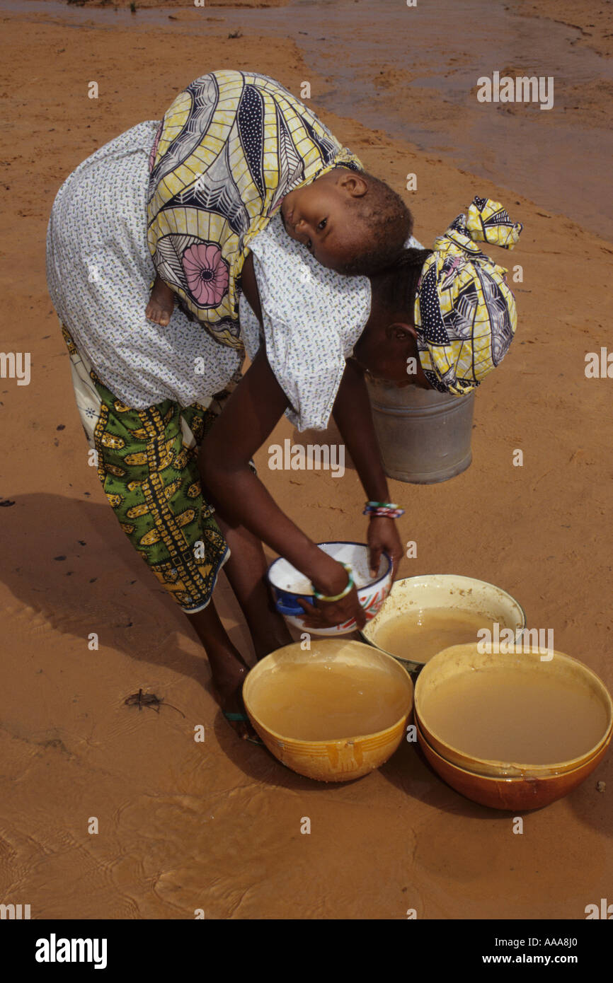 Près de Niamey, Niger, Afrique. Mère lave-vaisselle avec bébé au dos Banque D'Images