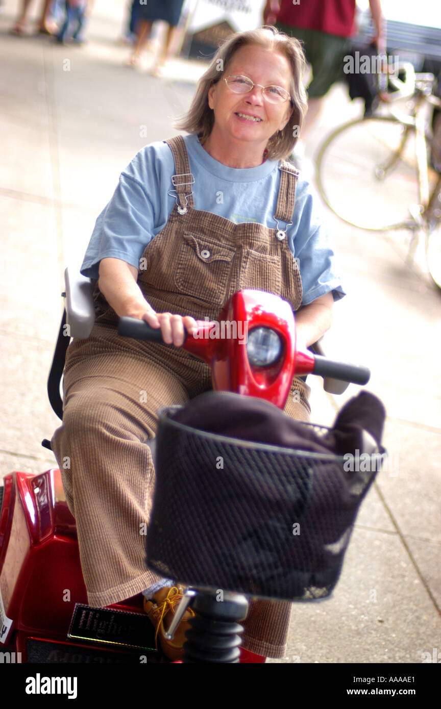 Pris sa retraite mobilité woman riding un fauteuil roulant motorisé. Banque D'Images