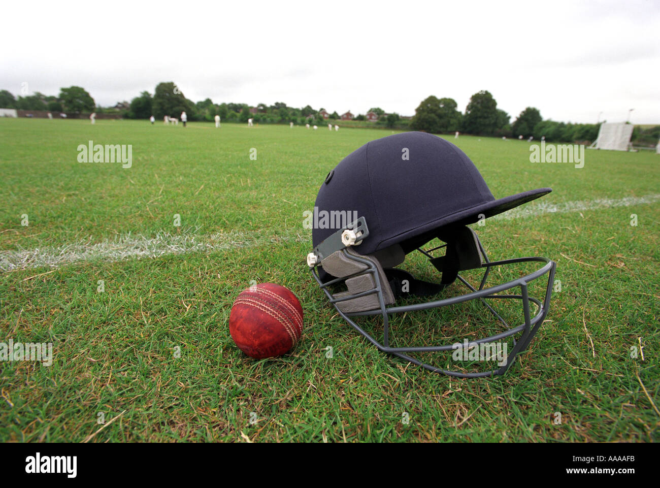 Un casque de cricket et la bille avec un match ayant lieu dans l'arrière-plan Banque D'Images