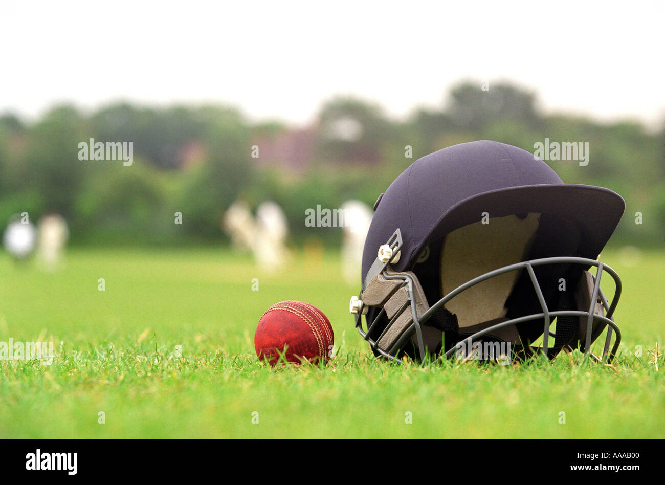 Un casque de cricket et la bille avec un match ayant lieu dans l'arrière-plan Banque D'Images
