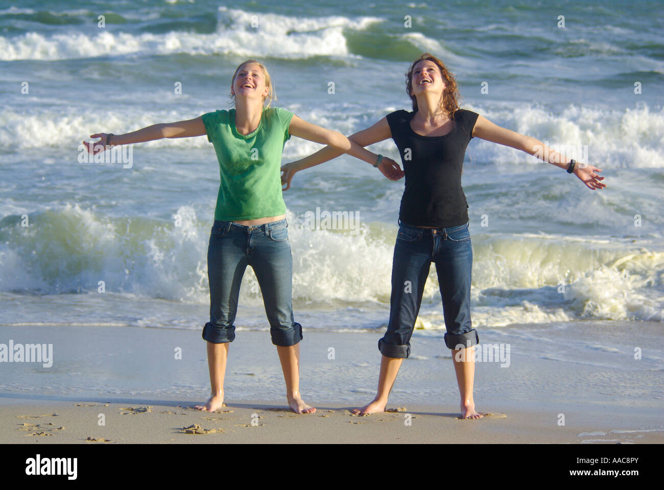 Deux adolescentes souriant avec bras tendus à côté mer Banque D'Images