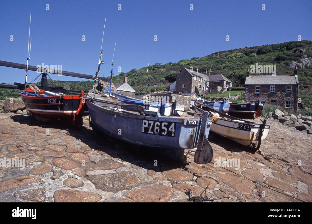 Penberth Cove sélection de petits bateaux de pêche assortis sur le pavage de pierre en pente abrupte avec des maisons de campagne au-delà du jour du ciel bleu ensoleillé Cornwall Angleterre Royaume-Uni Banque D'Images