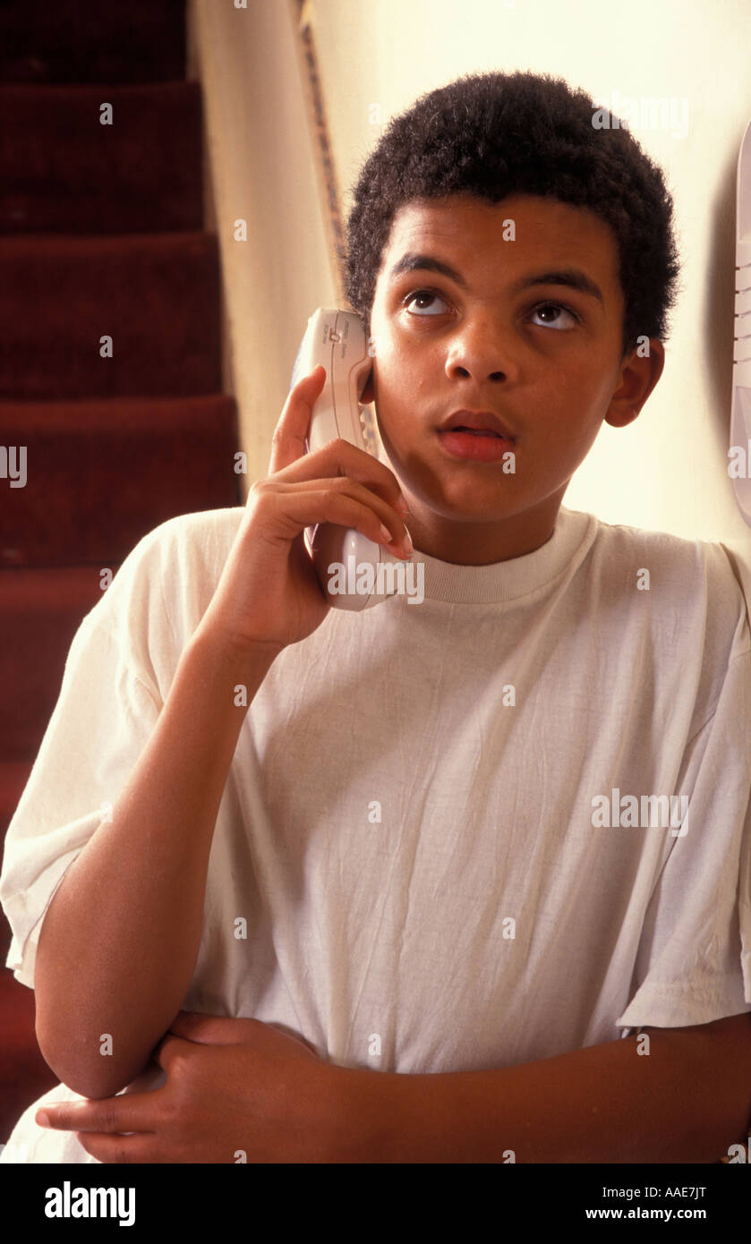 Mixed Race boy autour de 13 ans parlant le housephone portable avec impatience Banque D'Images