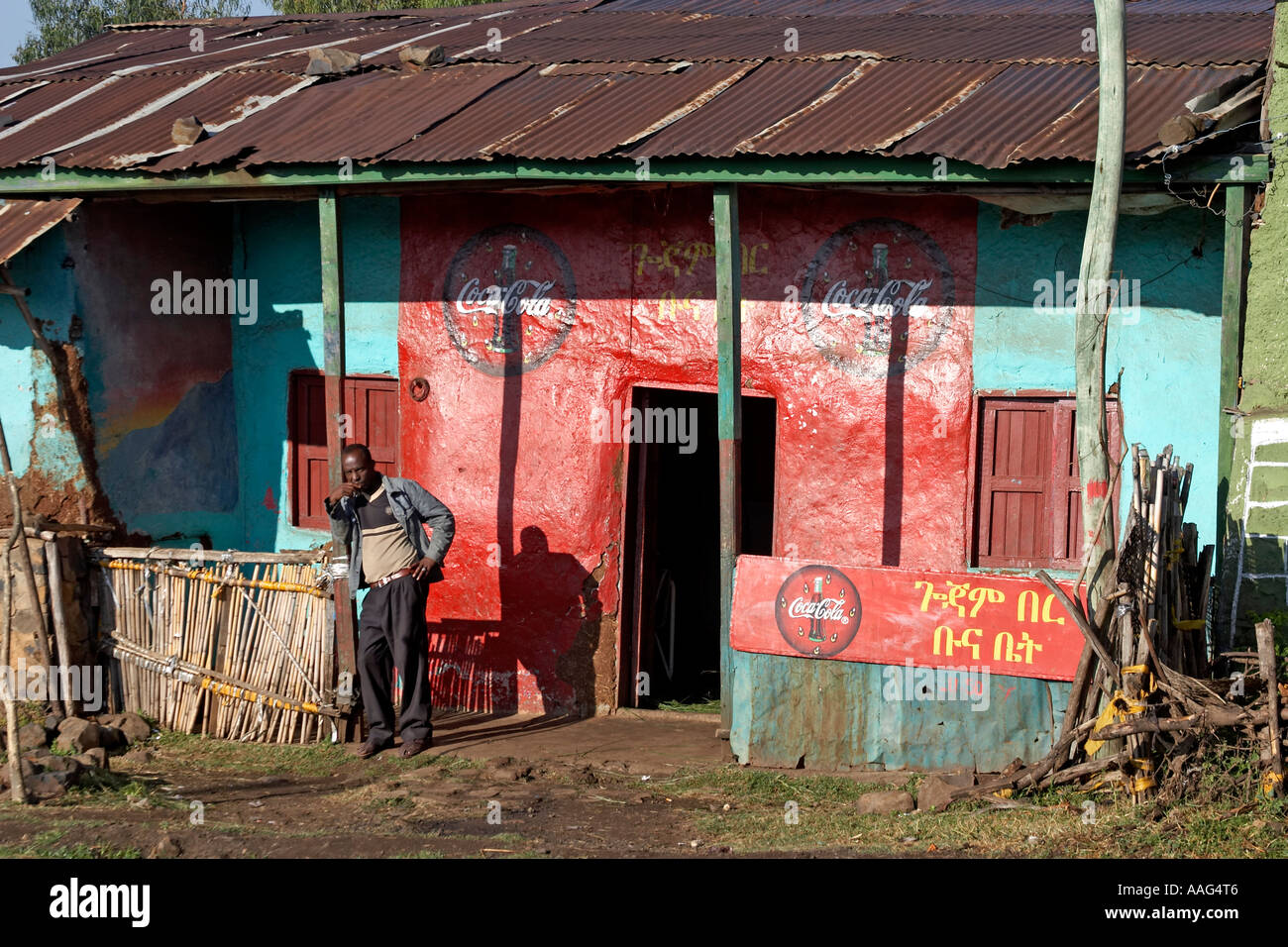 Homme debout à l'extérieur de l'atelier avec Coca Cola signes dans village de Dejen près de Shafartak Afrique Ethiopie pont Banque D'Images