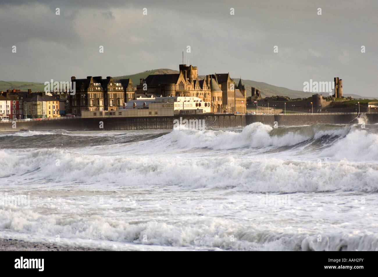 Mer agitée et de grosses vagues Aberystwyth, avec pier, ancien collège des bâtiments de l'université et d'anciennes ruines de château en arrière-plan, UK Banque D'Images