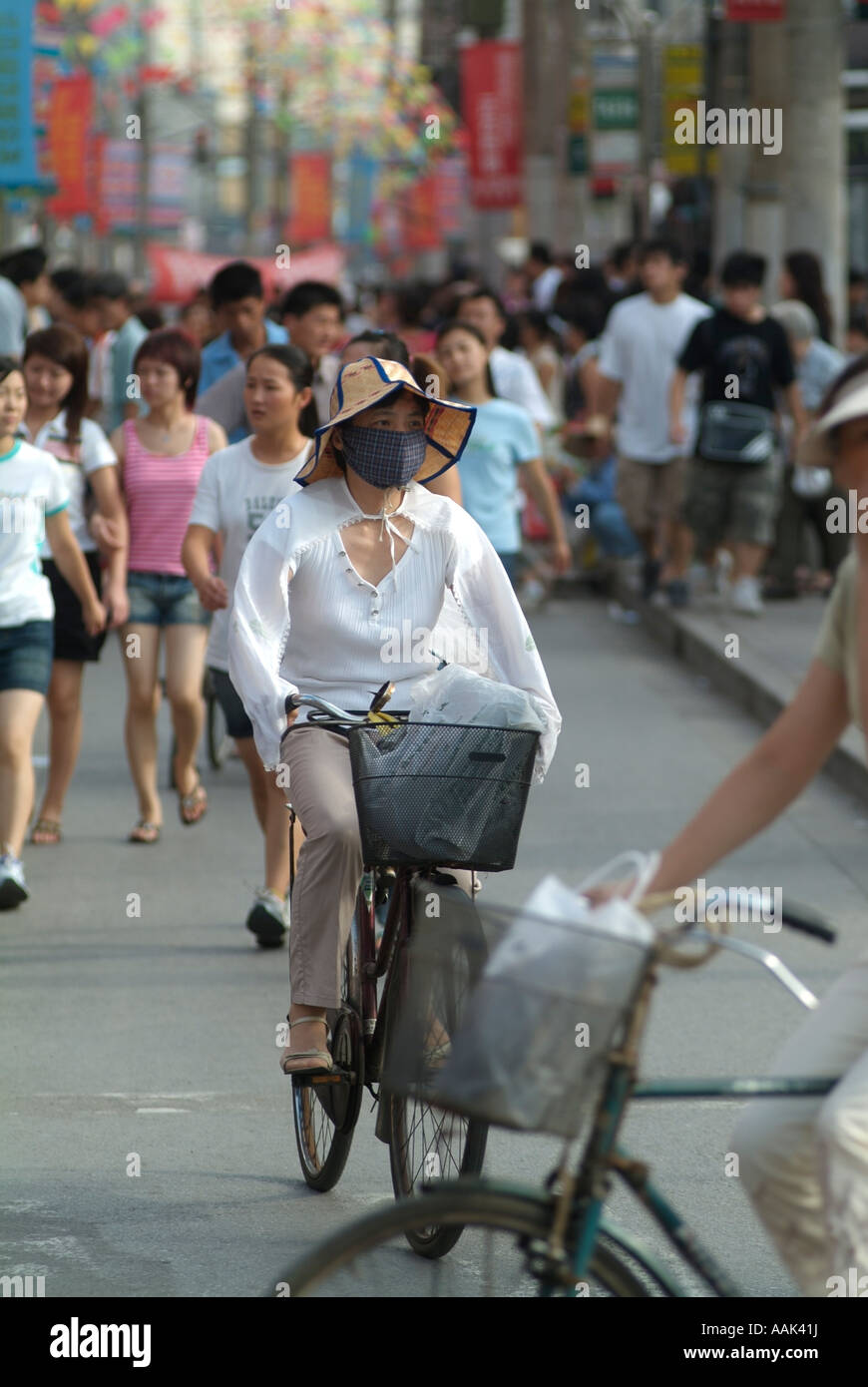 Femme portant un masque chinois comme elle chevauche son vélo près de Xiangyang Road à Shanghai Chine Photo par Chuck Nacke Banque D'Images