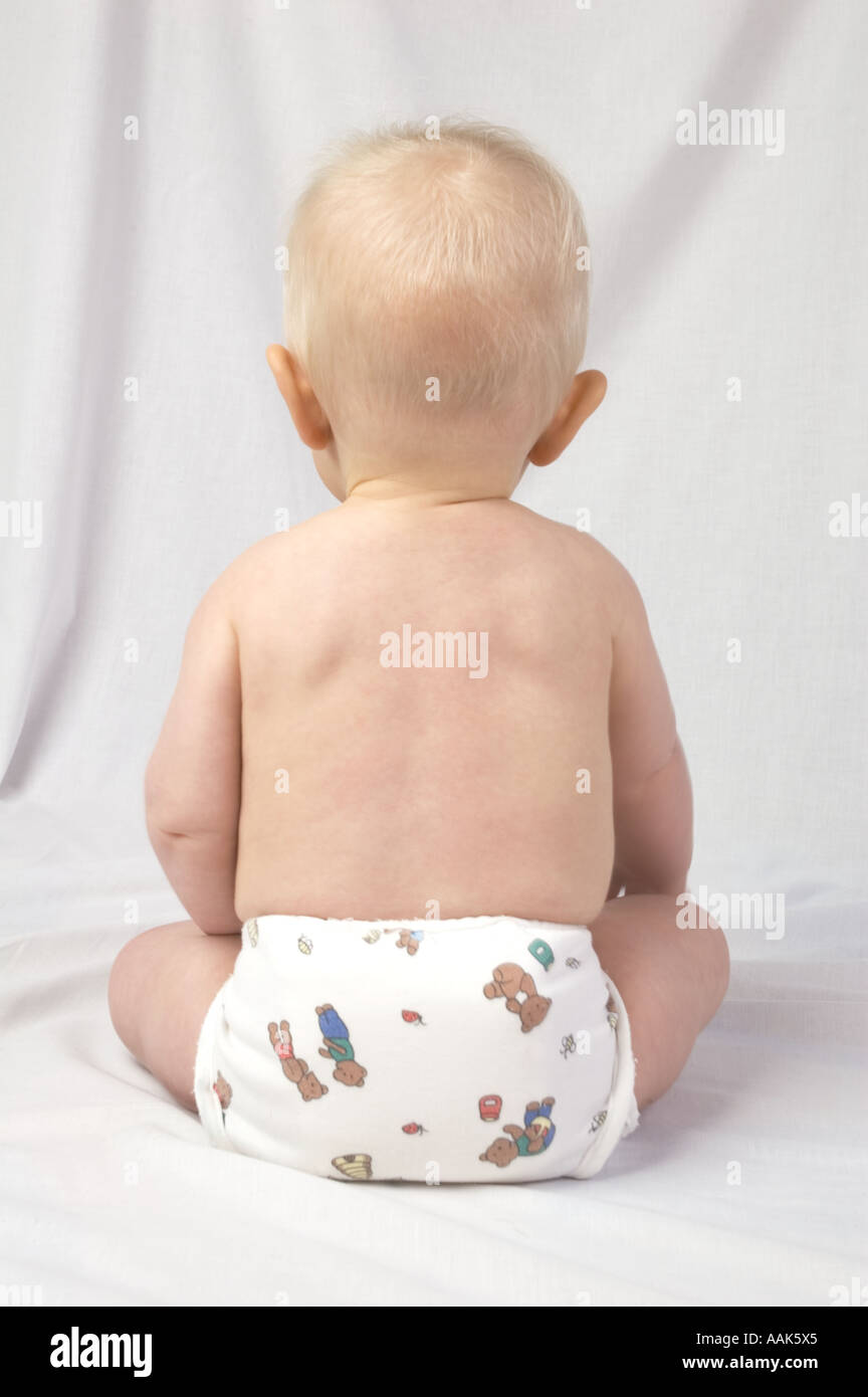 Simple image de l'arrière d'un bébé assis portant un nappy contre un arrière-plan uni, blanc Banque D'Images Simple image de l'arrière d'un bébé assis portant un nappy contre un arrière-plan uni, blanc Banque D'Images