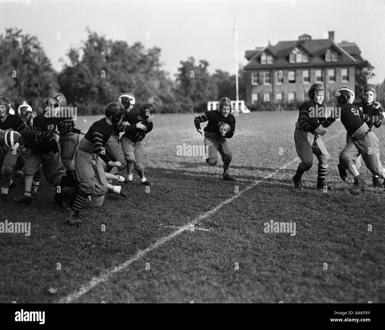 1930 L'école de garçons de l'ÉQUIPE DE FOOTBALL BOY RUNNING WITH BALL CENTER Banque D'Images