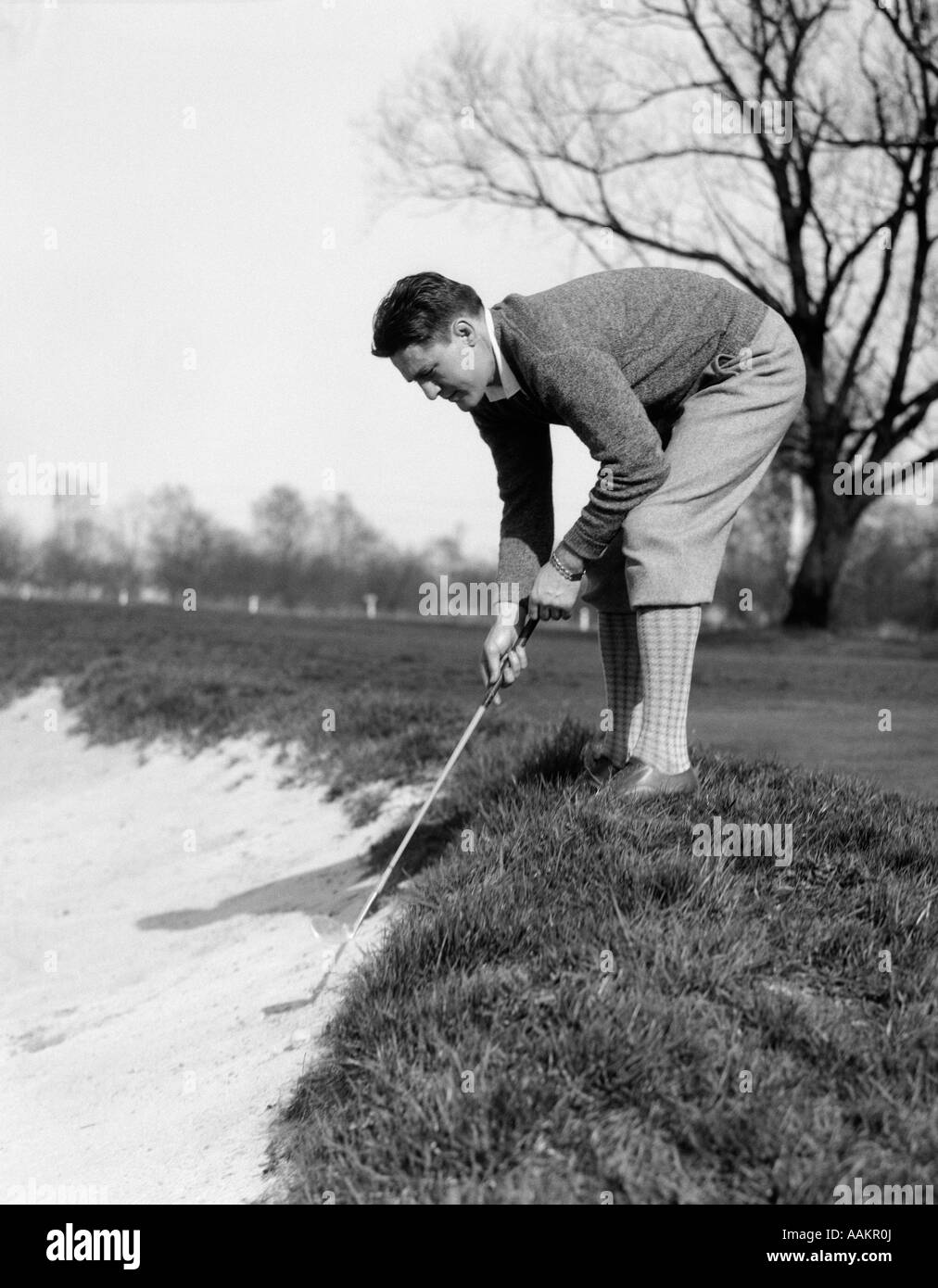 1930 golfeur homme jouer au ballon dans la FOSSE DE SABLE Banque D'Images