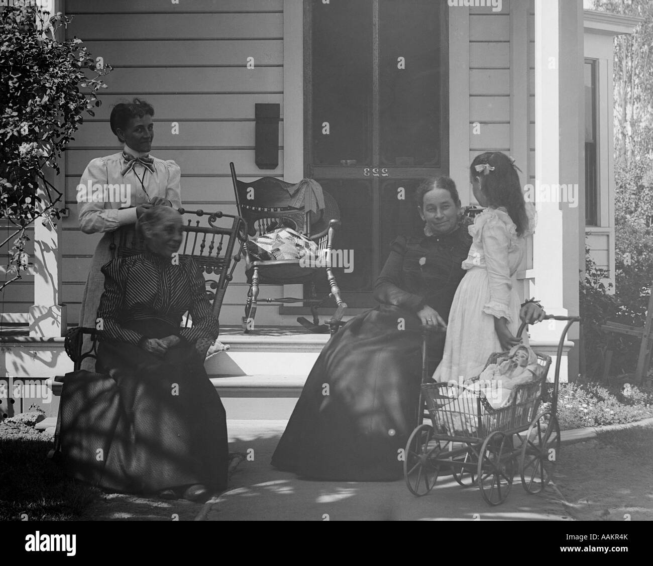 Années 1890 Années 1900 JEUNE ENFANT POUSSANT EN Poupée Poussette visiter trois femmes d'âge mûr assis dehors, portique de l'accueil Banque D'Images