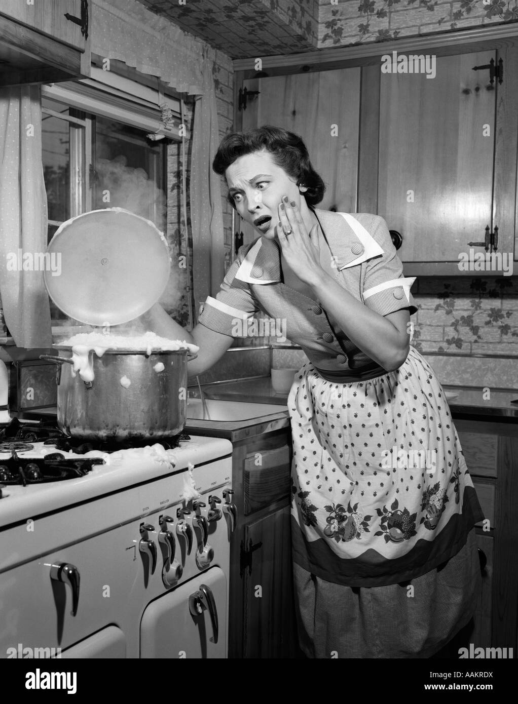 1950 FEMME AU FOYER FEMME HORRIFIÉE PRENANT COUVERCLE DE CASSEROLE PLUS Bouillante Banque D'Images