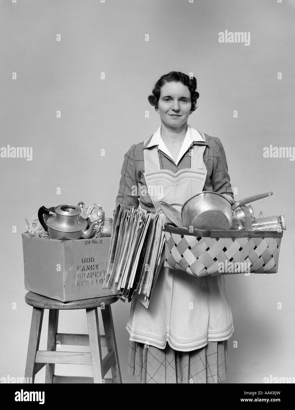 1940 FEMME CAMÉRA MÉNAGÈRE HOLDING BASKET REMPLIE DE POTS DE CUISINE CASSEROLES EN ALUMINIUM ET DE JOURNAUX Banque D'Images