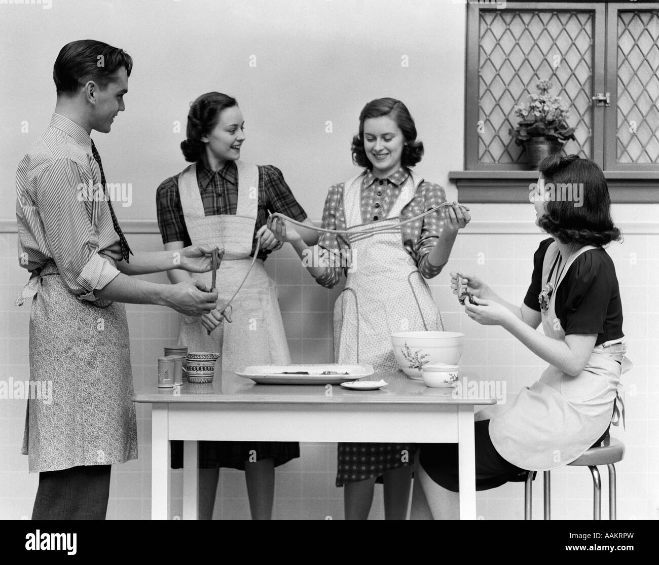 Années 1930 Années 1940 FEMMES 1 tabliers de cuisine HOMME EN TIRANT TAFFY Banque D'Images