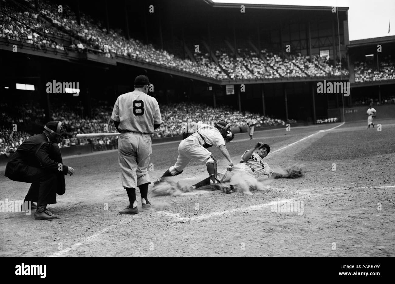 Années 1950 et juge-arbitre d'un match de baseball BATTER REGARDEZ COMME CATCHER PROTÈGE LA PLAQUE TOUT EN RUNNER COULISSE DANS ESSAYANT DE VOLER HOME Banque D'Images