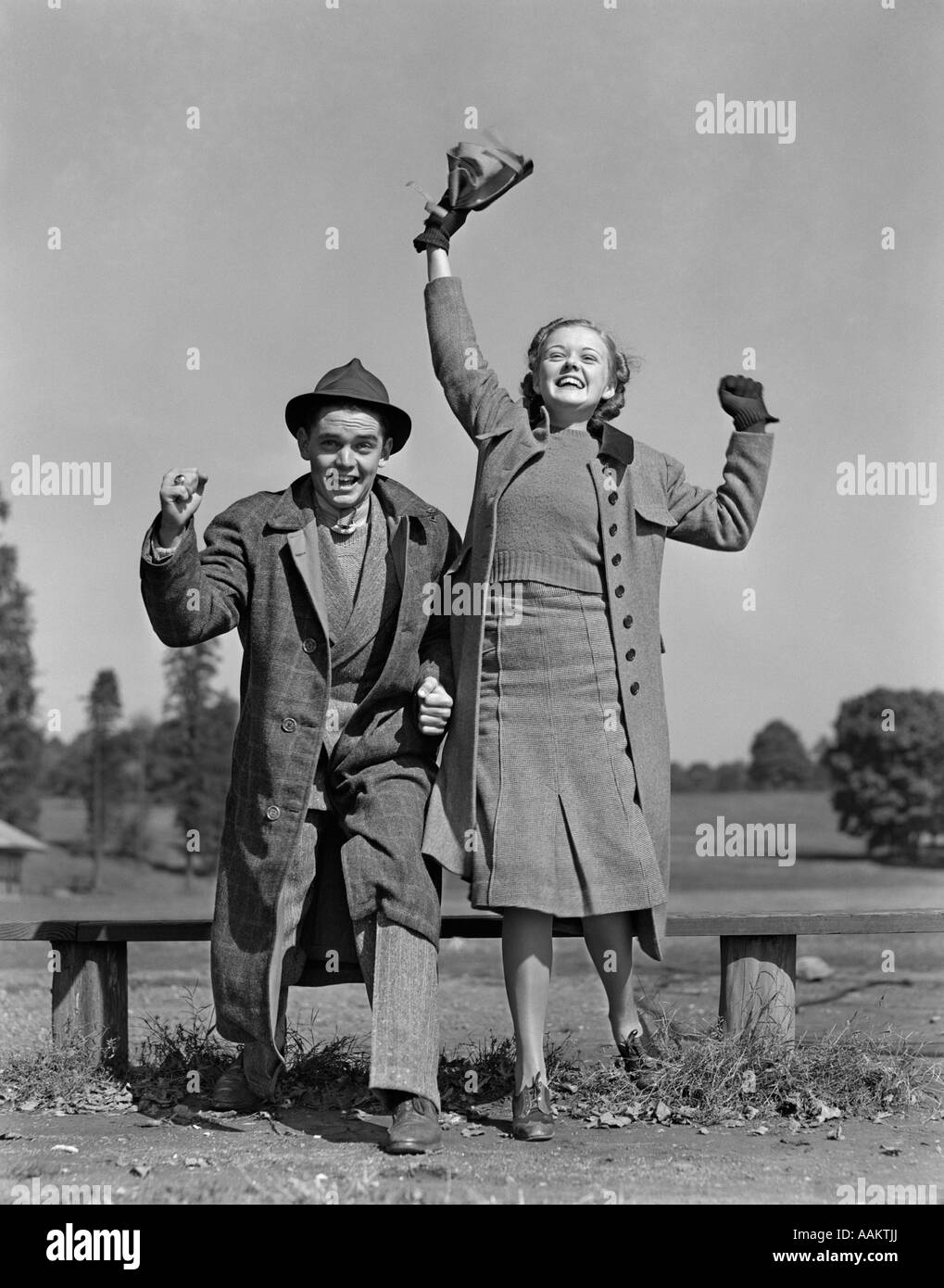 1940 YOUNG TEEN COUPLE Garçon Fille banc portant des manteaux de spectateurs heureux heureux événement sportif Banque D'Images