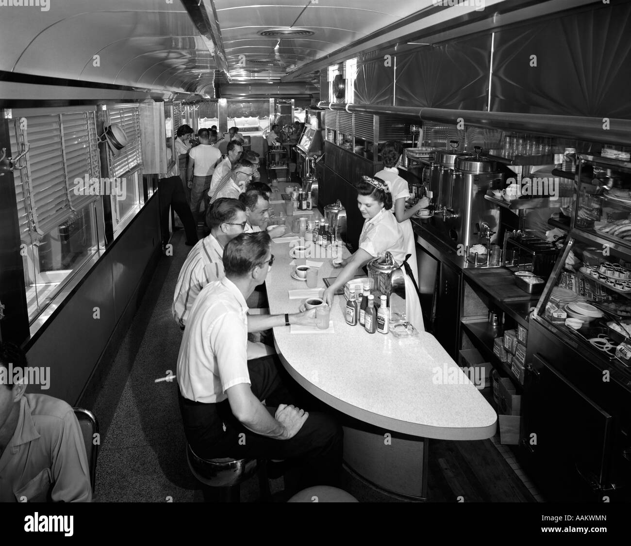 1960 INTÉRIEUR D'UN DINER AVEC LES CLIENTS assis au comptoir et les serveuses sont à leur service je Banque D'Images