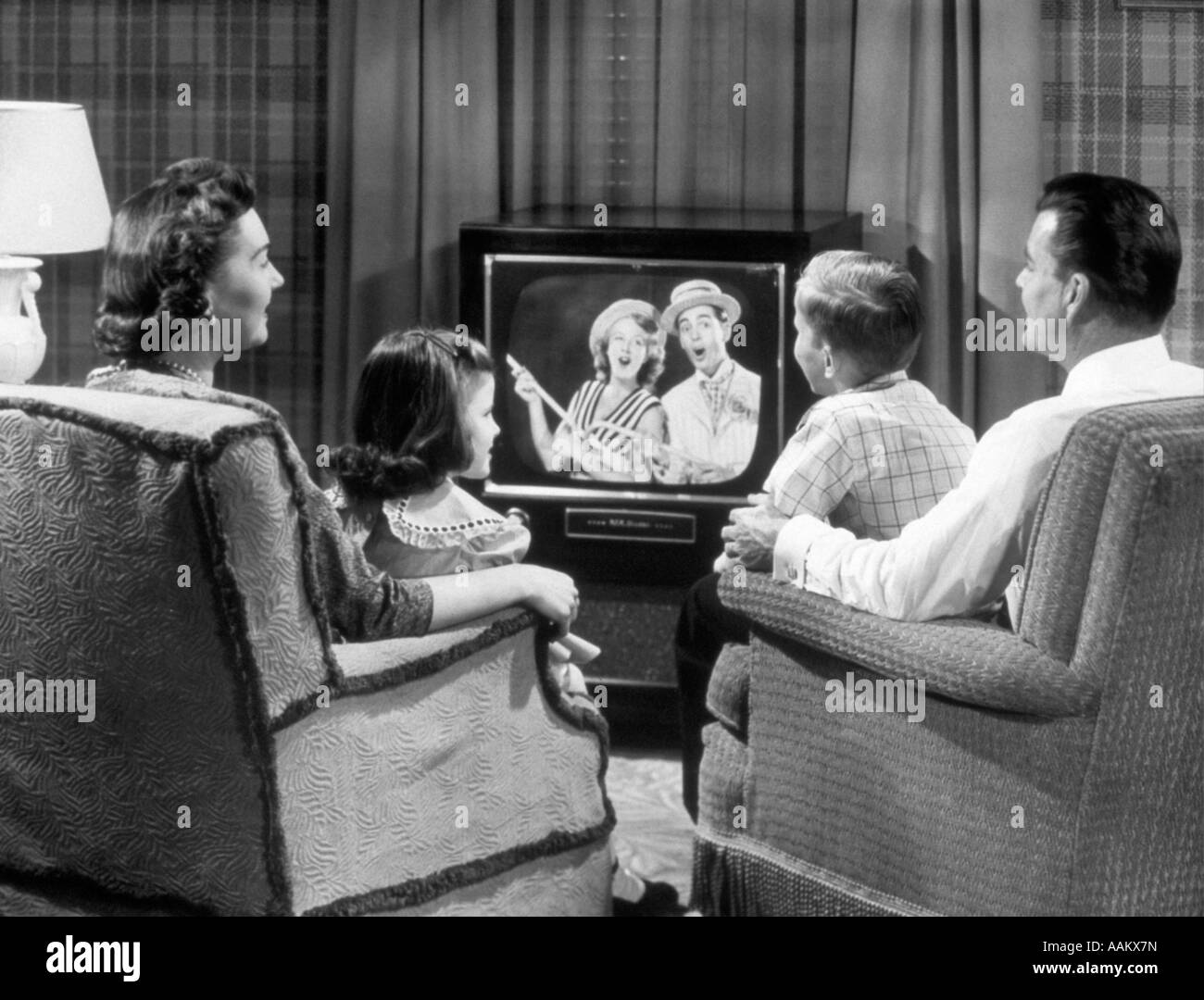 1950 FAMILLE ASSIS DANS UN FAUTEUIL À REGARDER LA TÉLÉVISION Banque D'Images