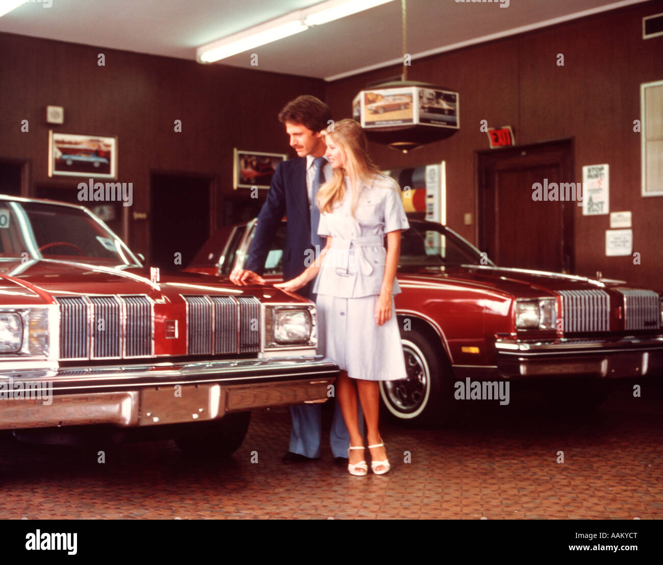 1960 COUPLE LOOKING AT CAR DANS SHOW ROOM Banque D'Images