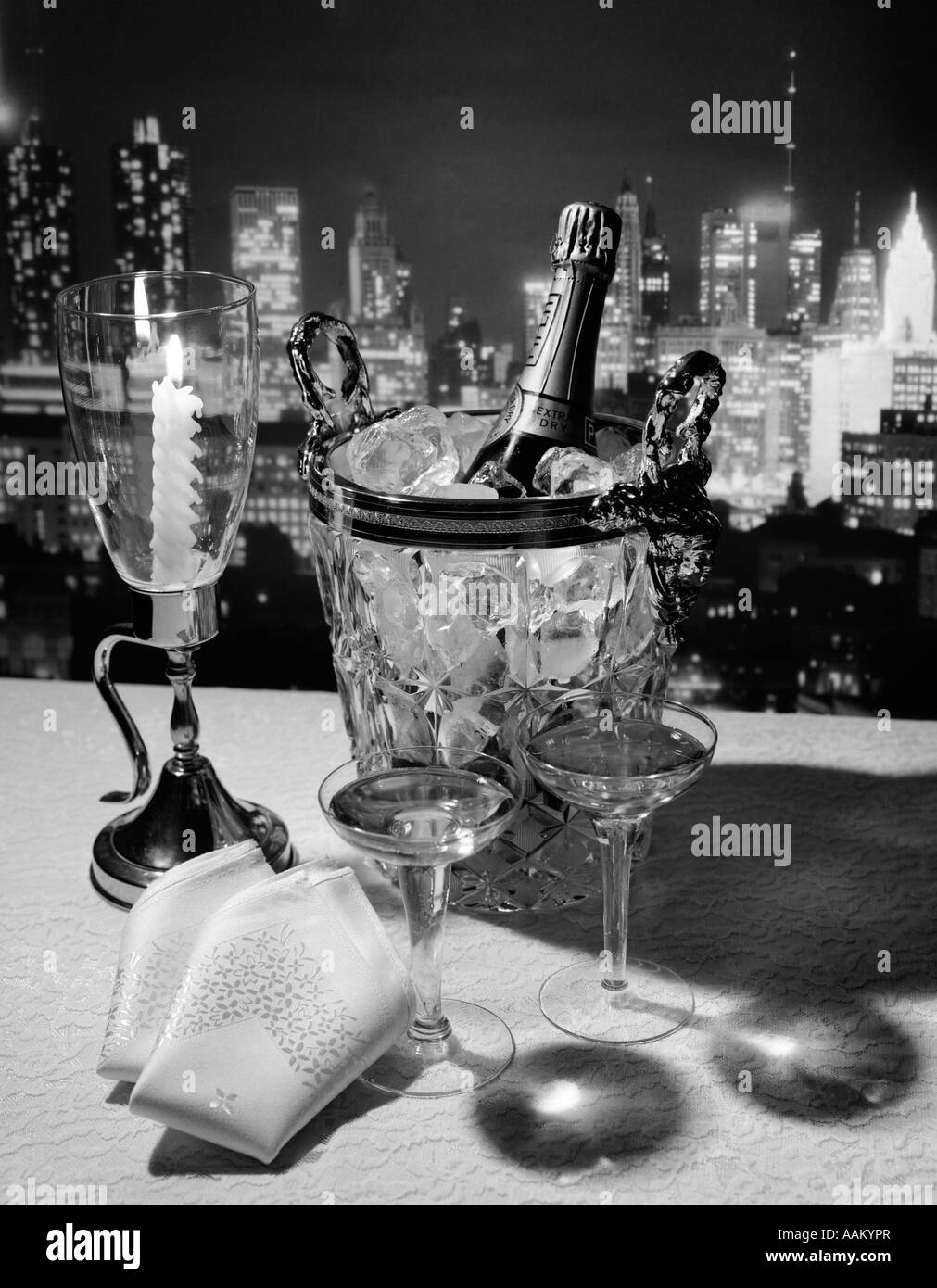 Bouteille de champagne dans un seau à glace avec des verres et des bougies SUR LA TABLE SERVIETTES & NEW YORK CITY NIGHT SKYLINE EN ARRIÈRE-PLAN Banque D'Images