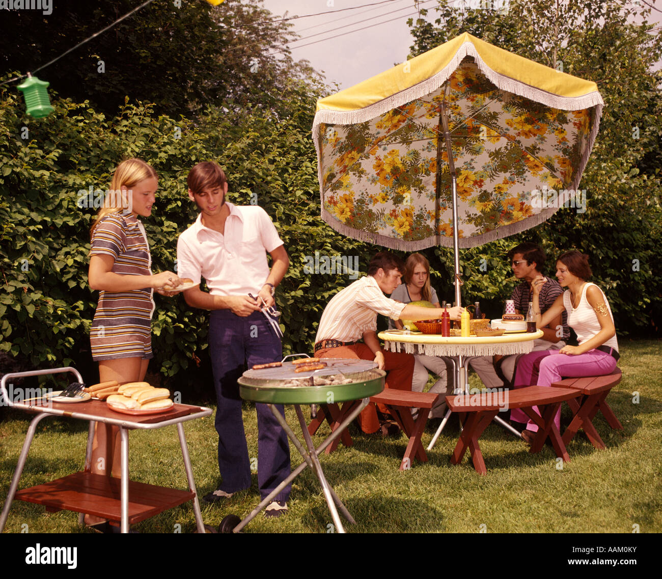 Groupe des années 1970, LES ADOLESCENTS Garçons Filles TABLE CUISSON JARDIN PARASOL Banque D'Images