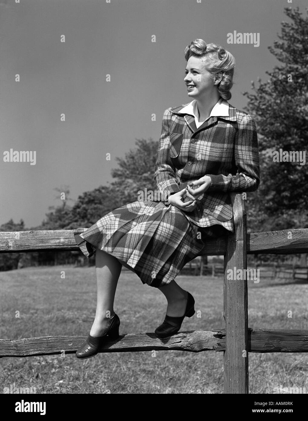 1940 PORTRAIT DE FEMME BLONDE ASSISE SUR UNE CLÔTURE EN BOIS PORTANT COSTUME TARTAN PLAID Banque D'Images