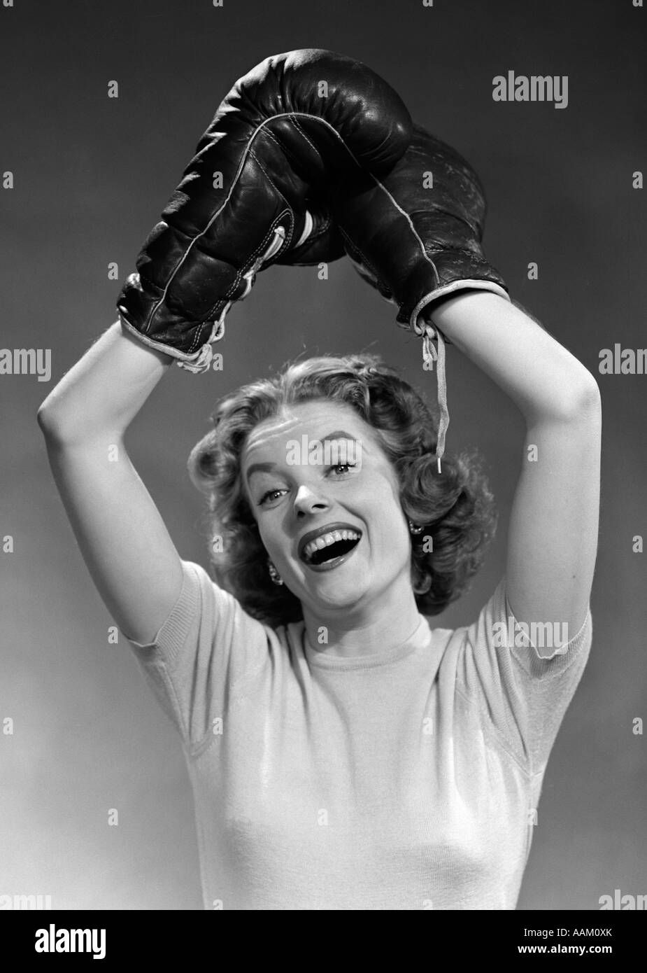 1950 Portrait de femme portant des gants de boxe en remportant posent bras levés PASSAGE LOOKING AT CAMERA Banque D'Images