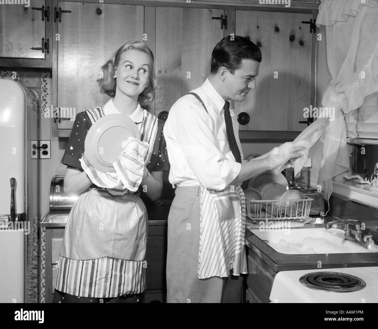 1950 SMILING HAPPY COUPLE HOMME ET FEMME MARI ET FEMME LAVE-VAISSELLE  ENSEMBLE DANS LA CUISINE Photo Stock - Alamy