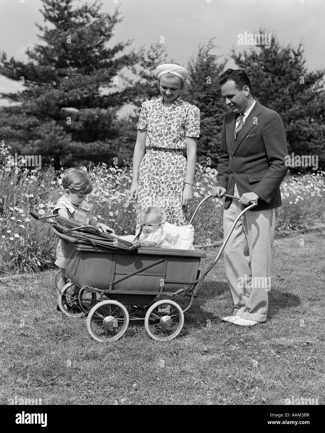 1930 PÈRE POUSSANT POUSSETTE DANS L'herbe avec mère & FILS À CÔTÉ DE LUI  Photo Stock - Alamy