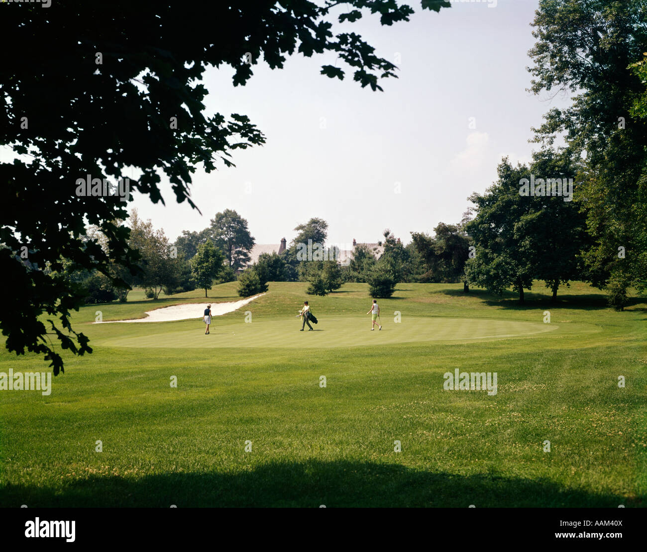 1970 TROIS PERSONNES jouant le GOLF À PIED À TRAVERS L'EXERCICE DES LOISIRS SPORTS GOLF Banque D'Images