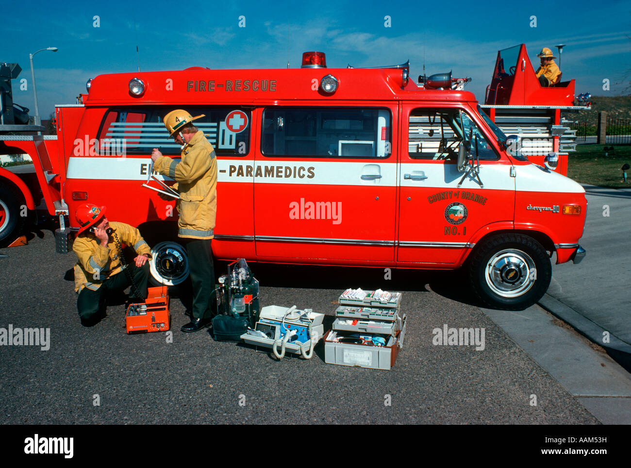 1970 1980 DEUX HOMMES de l'équipe paramédicale l'inspection de contrôle de l'ÉQUIPEMENT À PORTER DES CASQUES DE POMPIERS AMBULANCE VAN JACKETS Banque D'Images