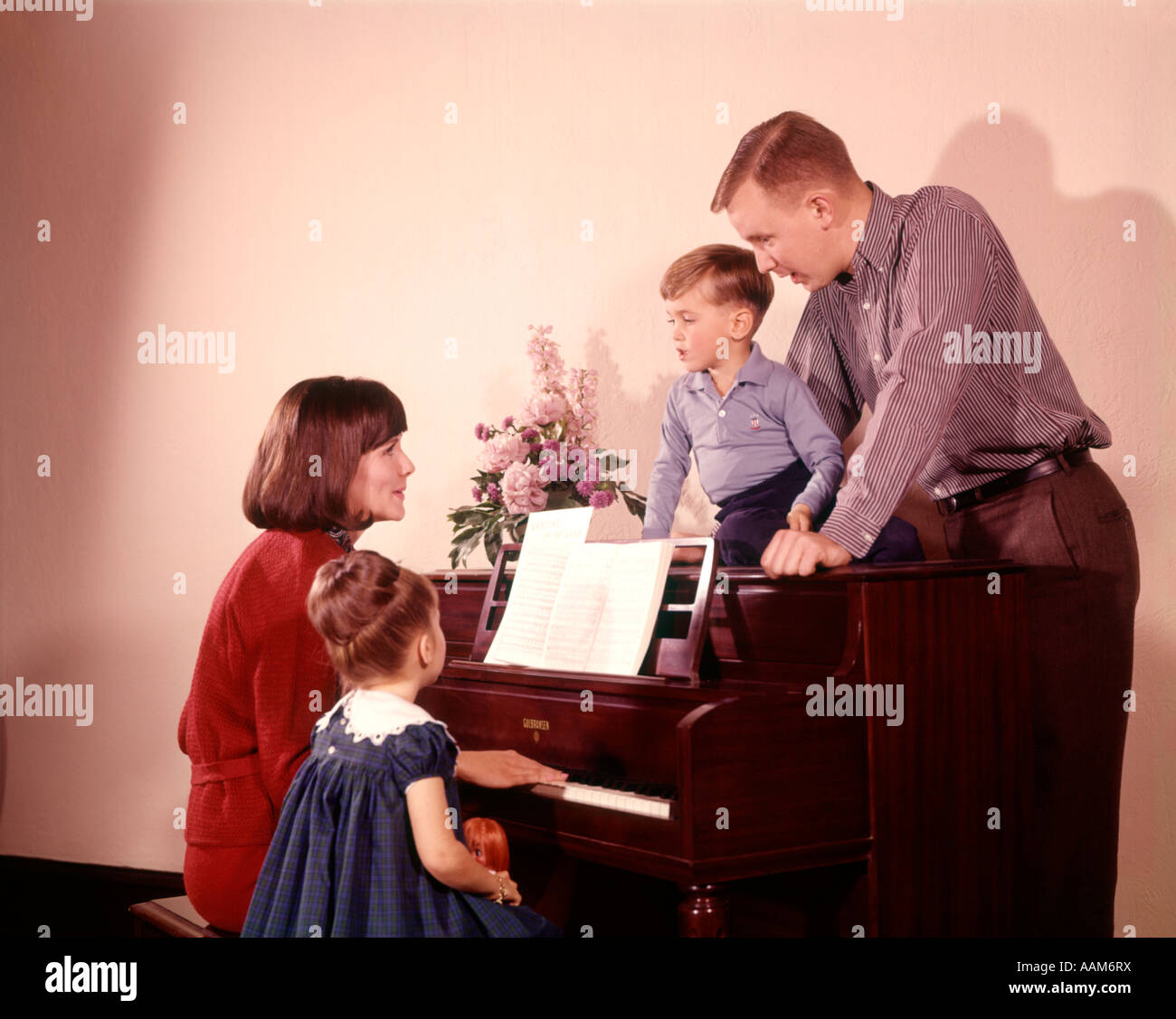 1960 1960 LE CHANT DE LA FAMILLE AUTOUR DE PIANO mère jouant de la musique ASSIS SUR BANC AVEC Fils Fille Fille Garçon au piano Banque D'Images