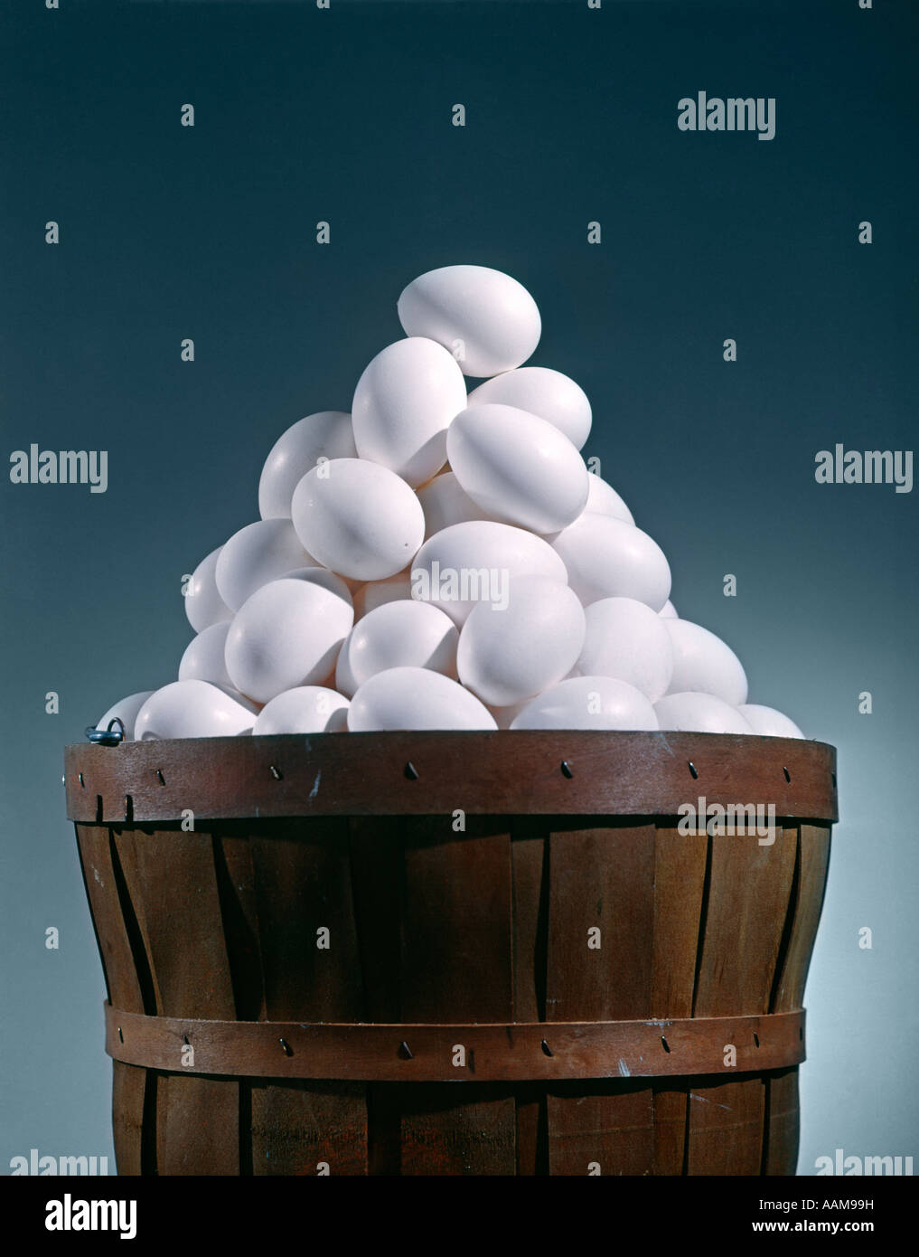 Le boisseau EN BOIS BRUN PANIER PLEIN DE BLANC DE POULET OEUFS DANS UN PANIER PYRAMIDE TRIANGLE Banque D'Images