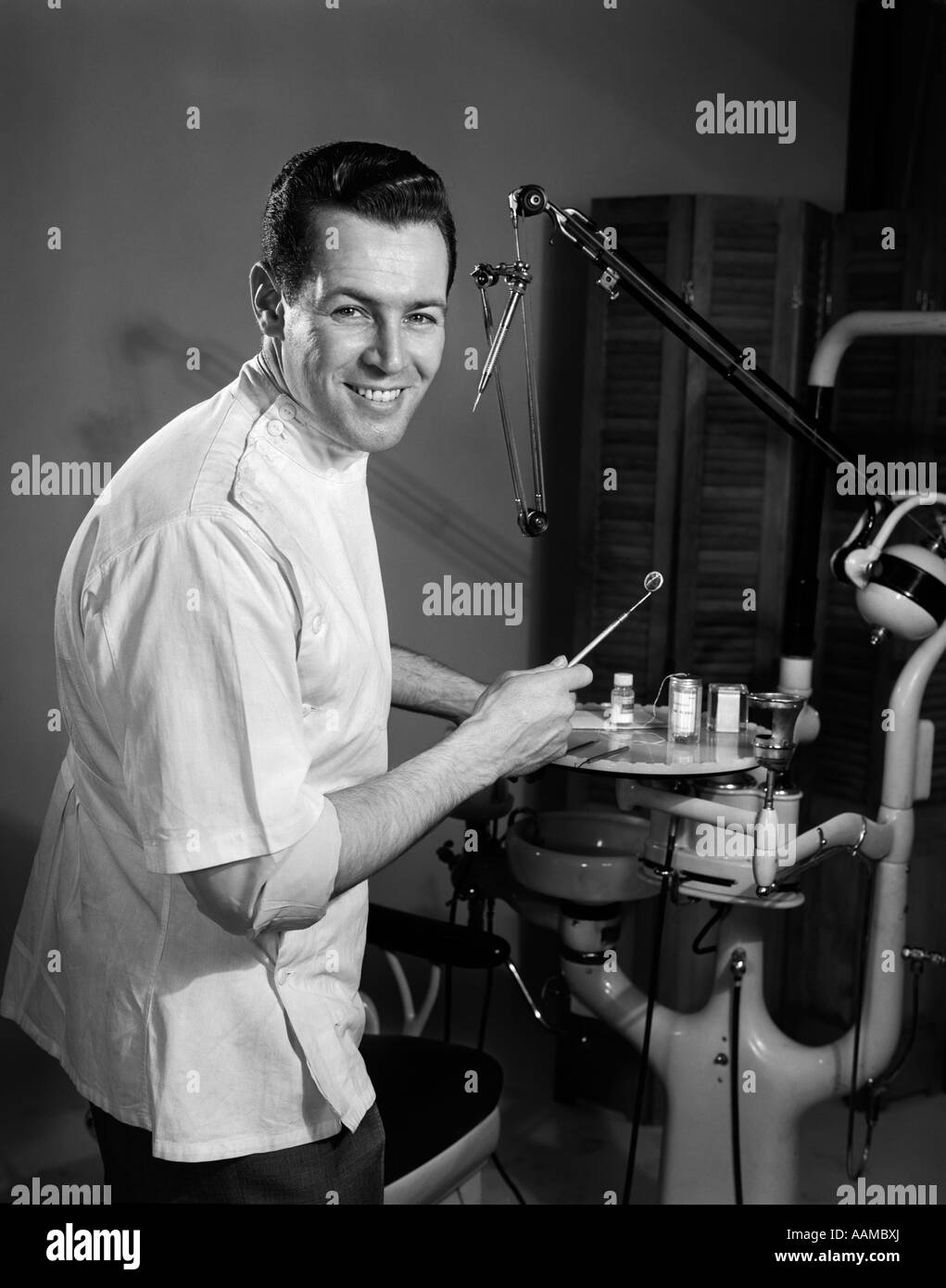 Années 1950 Années 1960 PORTRAIT SMILING MAN HOLDING DENTISTE PROFESSIONNEL MIROIR DENTAIRE LOOKING AT CAMERA Banque D'Images