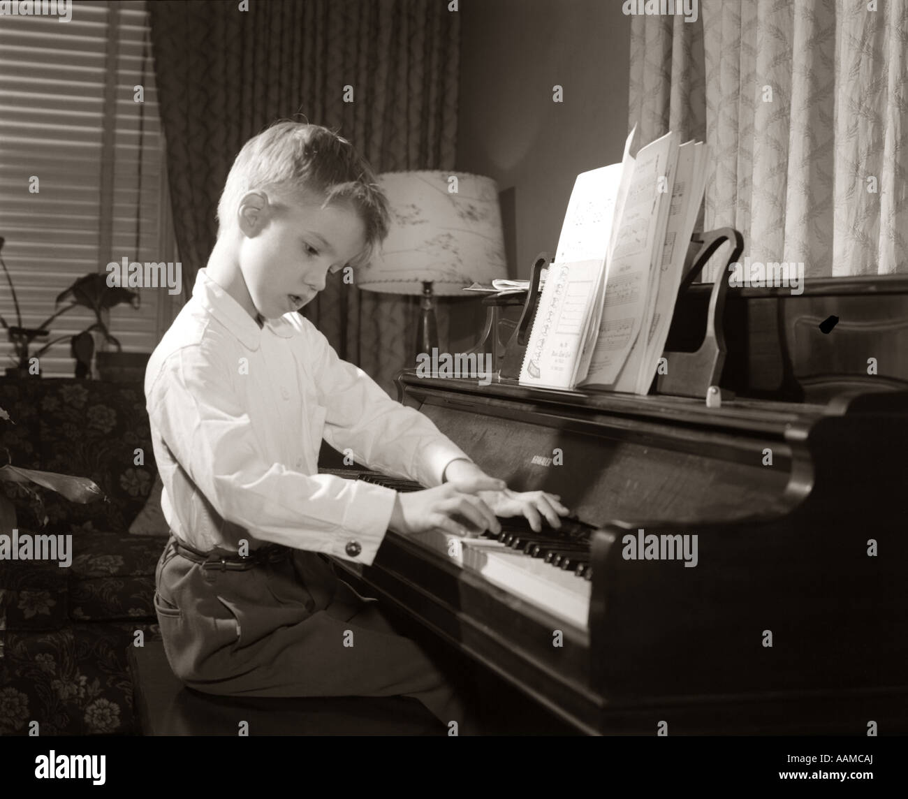 1950 BOY PRACTICING PIANO Leçon de musique jouant SCALES Banque D'Images
