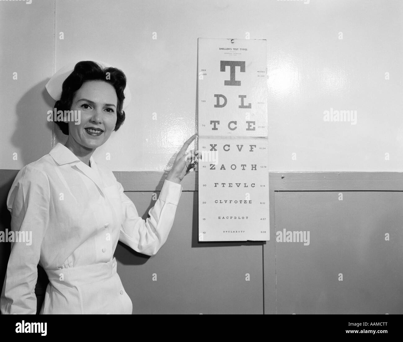 Années 1950 Années 1960 SMILING WOMAN INFIRMIÈRE pointant à l'œil Banque D'Images