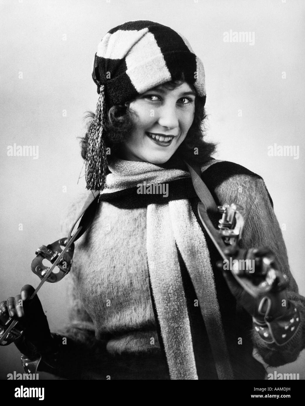 Années 1920 WOMAN WEARING SCARF PULL & HAT avec sangle sur patins à glace accroché autour du cou Banque D'Images