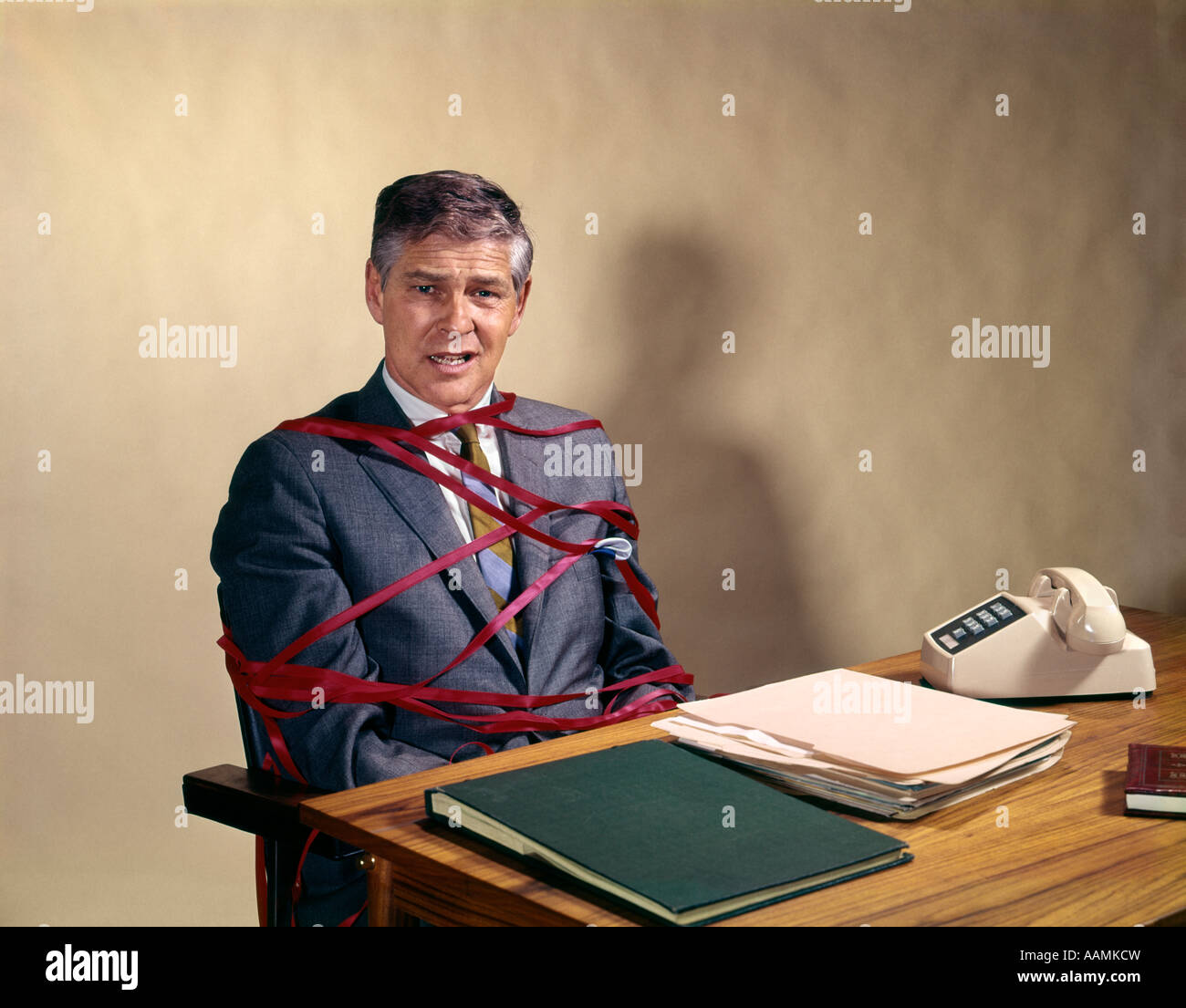 Des années 1970 à l'homme d'affaires d'âge moyen 24 attaché enchevêtré dans la paperasserie inutile bureaucratie SNAFU BUREAU RETRO VINTAGE Banque D'Images