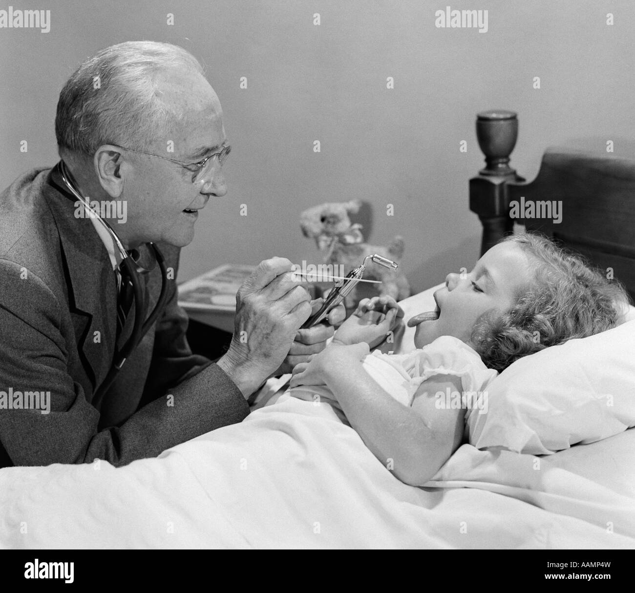 1950 Petite fille malade au lit convertible MÉDECIN SUR APPEL À LA MAISON À CÔTÉ DE LIT EN REGARDANT SA GORGE Banque D'Images