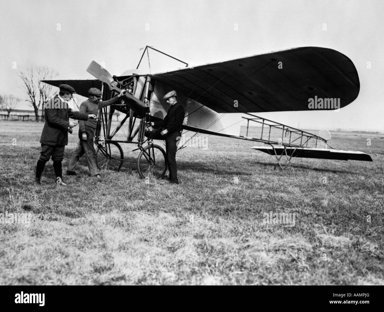 1910 GROUPE DE TROIS HOMMES DEBOUT DEVANT UN MONOPLAN PRÉCOCE AVEC MAIN SUR PROPELLER Banque D'Images