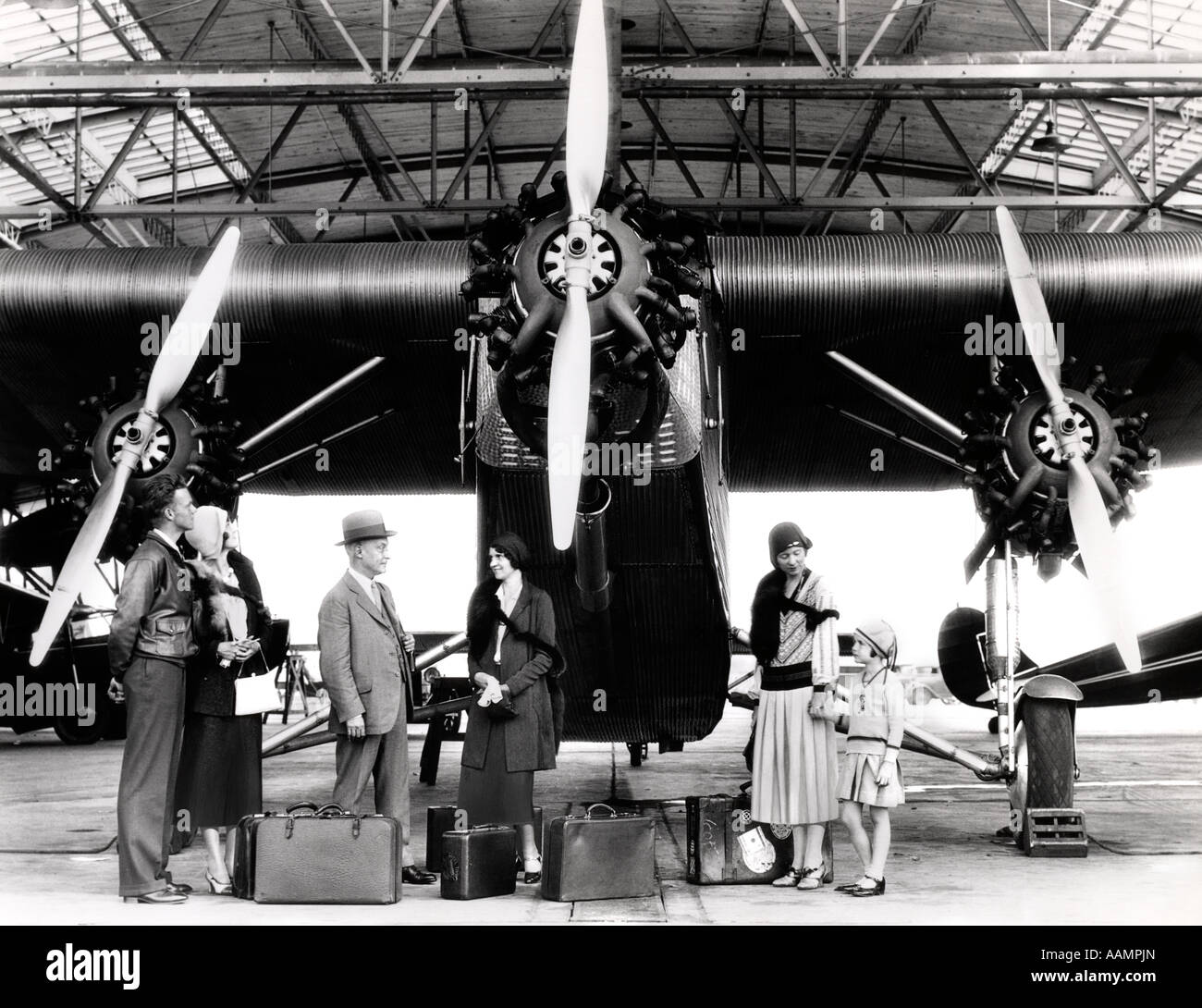Années 1920 Années 1930 GROUPE DE PASSAGERS EN ATTENTE DEVANT FORD TRI-AVION À MOTEUR Banque D'Images