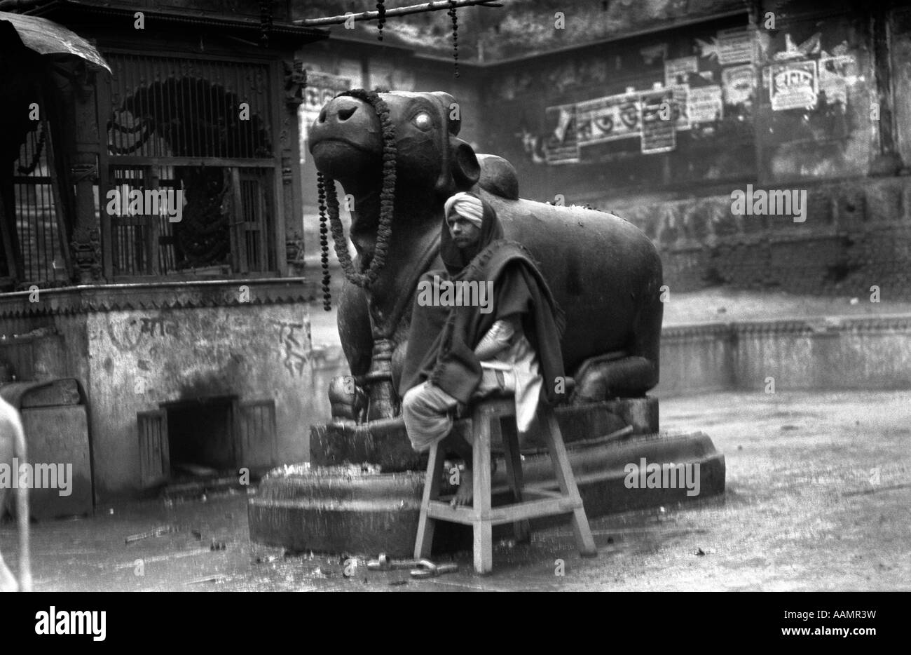 Années 1920 Années 1930 BÉNARÈS INDE HOMME EN TURBAN ASSIS PAR STATUE DE NANDI BULL Dieu sacré hindou HINDOUISME RELIGION Banque D'Images